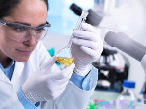 Scientist using flask to mix chemical compound during an experiment Scientist using flask to mix chemical compound during an experiment